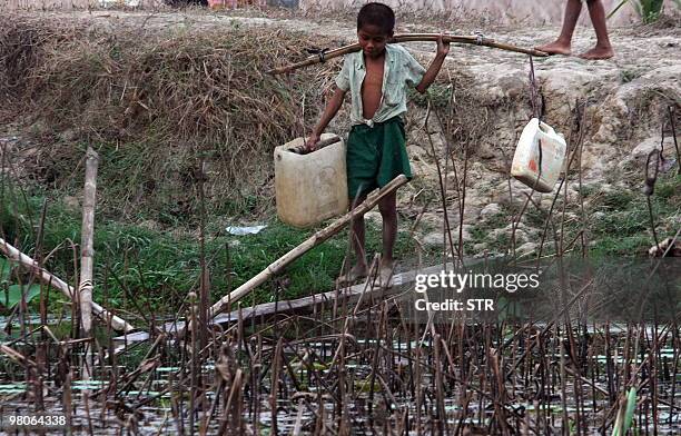 Photo taken on March 18, 2010 shows a Myanmar boy carrying plastic containers to fill up with water from a pond in a village near Yangon. As the...