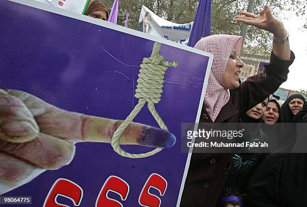 Supporters of Iraqi Incumbent Prime Minister Nouri al-Maliki chant anti-Baathist slogans during a protest as a poster showing hanged inked finger...