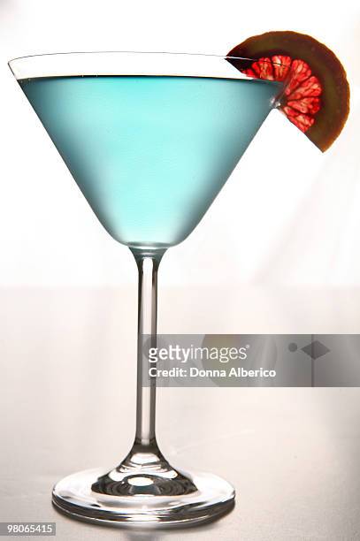 blue martini with blood red orange - blue martini glasses stock-fotos und bilder