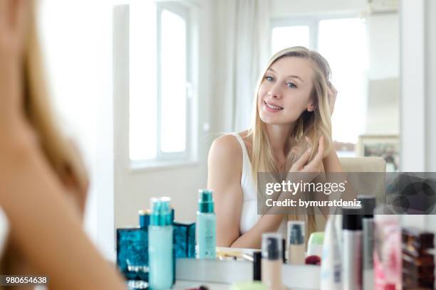 schöne frau, blick auf den spiegel - women haircare stock-fotos und bilder