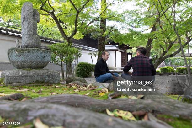 zwei männliche freunde sitzen im tempel - indischer subkontinent abstammung stock-fotos und bilder