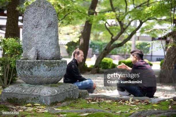 zwei männliche freunde sitzen im tempel - indischer subkontinent abstammung stock-fotos und bilder