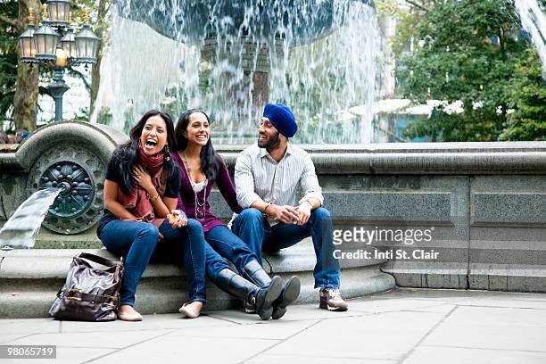 friends sitting by fountain talking and laughing - turbante fotografías e imágenes de stock
