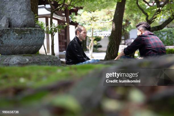 zwei männliche freunde sitzen im tempel - indischer subkontinent abstammung stock-fotos und bilder