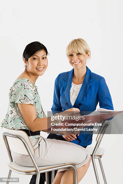 two smiling women sitting on chairs - david leahy studio stock pictures, royalty-free photos & images