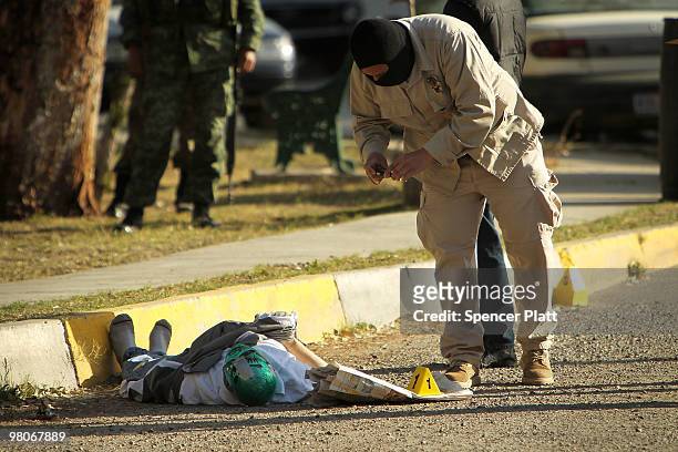 Criminal investigator takes a picture of a body with a mask in the street, one of numerous murders over a 24 hour period, on March 26, 2010 in...