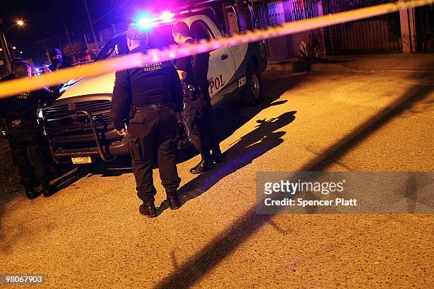 Police stand near the car where the body of a 13 year old boy lies dead, one of numerous murders over a 24 hour period, on March 25, 2010 in Juarez,...