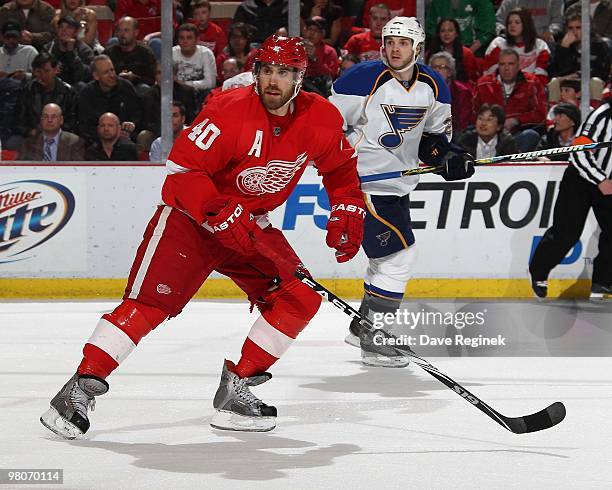 Henrik Zetterberg of the Detroit Red Wings skates next to Carlo Colaiacovo of the St. Louis Blues during an NHL game at Joe Louis Arena on March 24,...