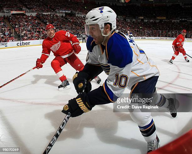Andy McDonald of the St.Louis Blues skates along the boards as Brad Stuart of the Detroit Red Wings defends during an NHL game at Joe Louis Arena on...