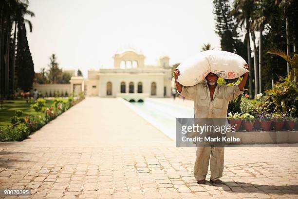 Worker carries a bag of grass clippings on his head at the Yadavindra Gardens on March 26, 2010 in Pinjore, India.