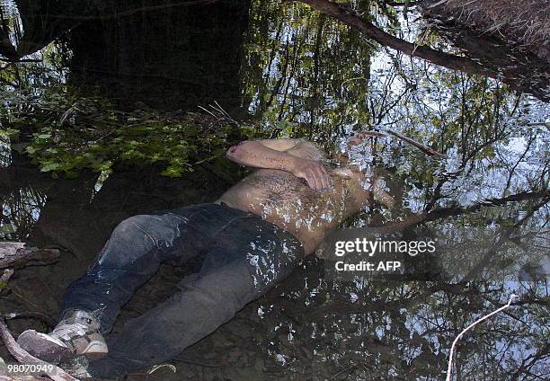 Corpse lies half-inmersed in a stream at the Cerralvo community, in Nuevo Leon state, Mexico on March 25, 2010. Last nigth six gunmen were killed in...