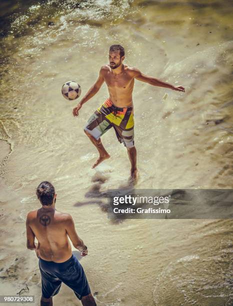 two young brazilian men playing soccer on copacabana beach on a hot summer day in rio de janeiro brazil - grafissimo stock pictures, royalty-free photos & images