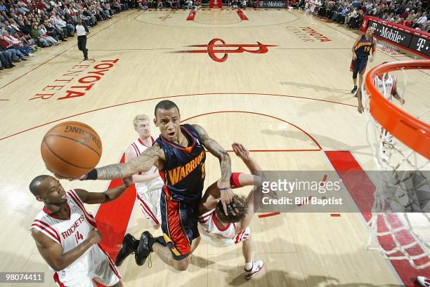 Monta Ellis of the Golden State Warriors takes the ball to the basket against David Andersen and Carl Landry of the Houston Rockets during the game...
