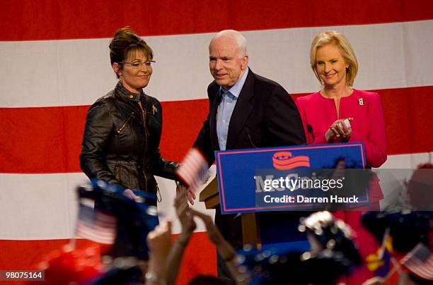 Sen. John McCain greets supporters as former Alaska Gov. Sarah Palin and his wife Cindy McCain look on during a campaign rally at Pima County...