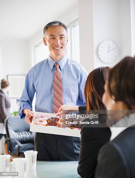 businessman holding tray of donuts at meeting - donut man stock pictures, royalty-free photos & images