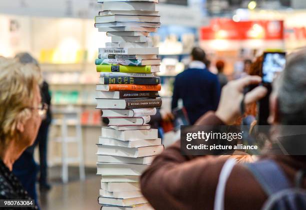 March 2018, Germany, Leipzig: Visitors photograph a stack of books at the stand of the Kiepenheuer und Witsch book publisher. This year's book fair...