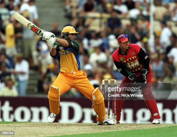 Michael Bevan of Australia cuts through point as wicketkeeper Andy Flower of Zimbabwe looks on during the Carlton Series One Day International...