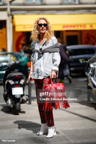 Elina Halimi wearsa shirt, red tartan checked pants, a red bag with fringes, outside Issey Miyake, during Paris Fashion Week - Menswear Spring-Summer...