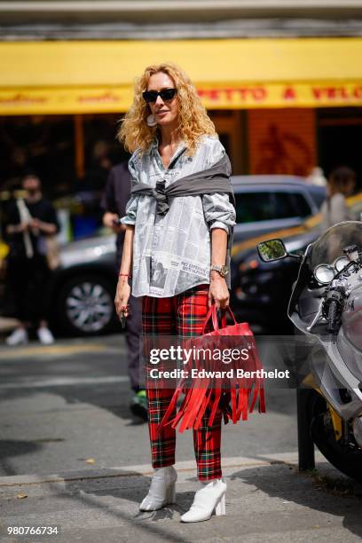 Elina Halimi wearsa shirt, red tartan checked pants, a red bag with fringes, outside Issey Miyake, during Paris Fashion Week - Menswear Spring-Summer...