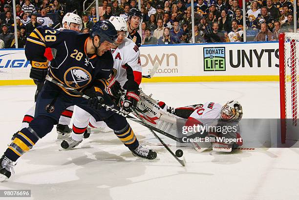 Chris Phillips and Brian Elliot of the Ottawa Senators make a save against Paul Gaustad of the Buffalo Sabres in their game on March 26, 2010 at HSBC...