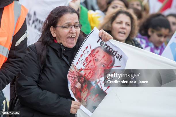 Kurdish woman hold up a sign with an image of the Turkish president Erdogan during a demonstration against the ongoing Turkish military offensive...