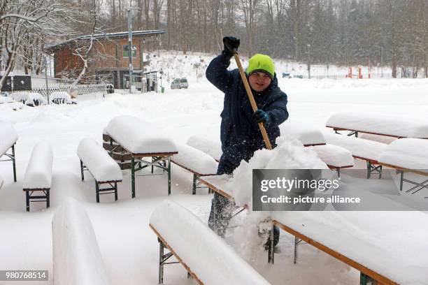 March 2018, Germany, Hasselfelde: An employee of a restaurant clears snow from tables using a snow shovel Photo: Matthias Bein/dpa-Zentralbild/dpa