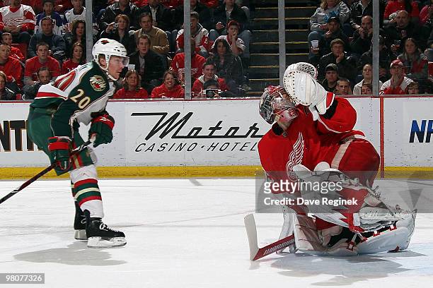 Antti Miettinen of the Minnesota Wild takes a shot as Jimmy Howard of the Detroit Red Wings makes a save during an NHL game at Joe Louis Arena on...
