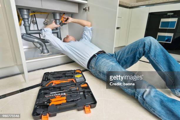 man repairing sink pipe in the kitchen - under sink stock pictures, royalty-free photos & images