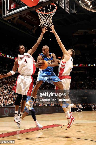 Chauncey Billups of the Denver Nuggets looks to pass out of the paint between Chris Bosh and Andrea Bargnani of the Toronto Raptors during a game on...