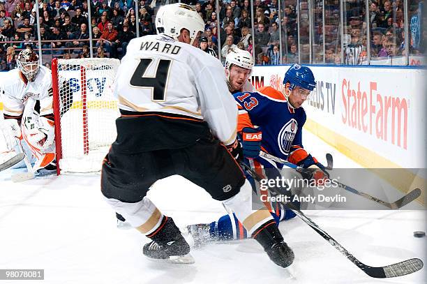 Andrew Cogliano of the Edmonton Oilers fights for the puck from his knees against Todd Marchant and Aaron Ward of the Anaheim Ducks at Rexall Place...