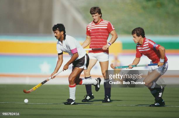 Kenyan field hockey player Brajinder Daved makes a run with the ball as Sean Kerly of Great Britain looks on during the pool B game between Great...