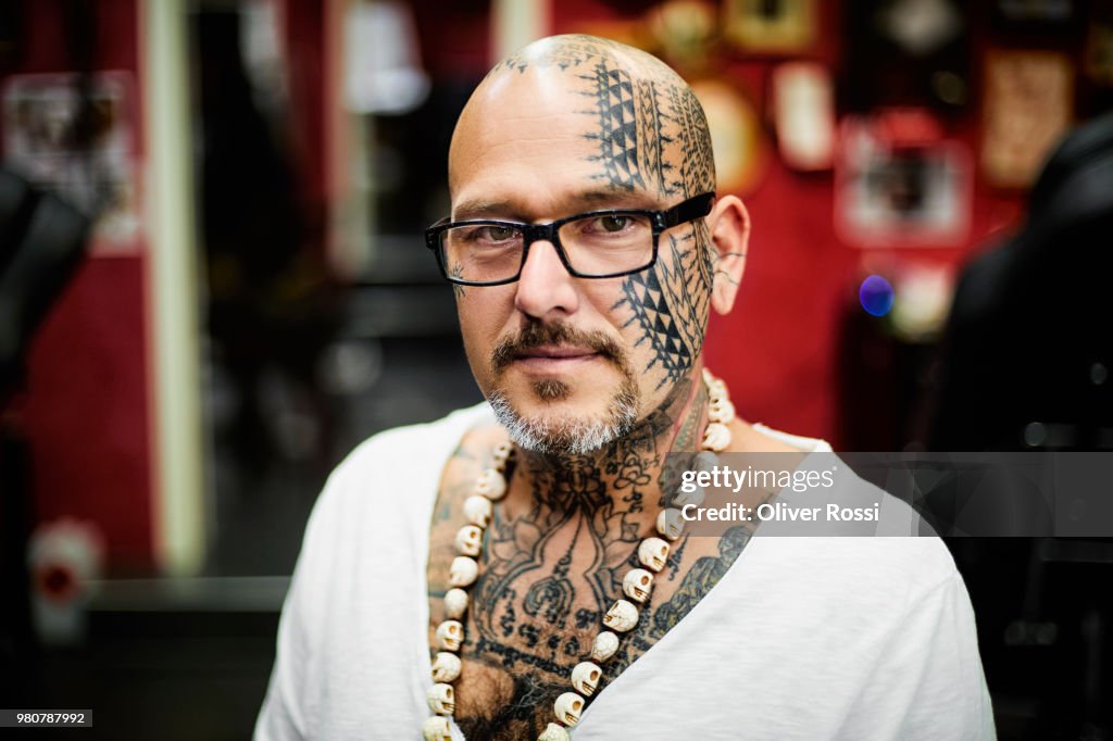 Portrait of confident tattooist wearing skull necklace in his studio