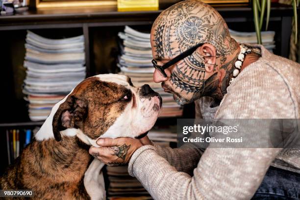 tattooed man face to face with his dog - men doing quirky things stock-fotos und bilder