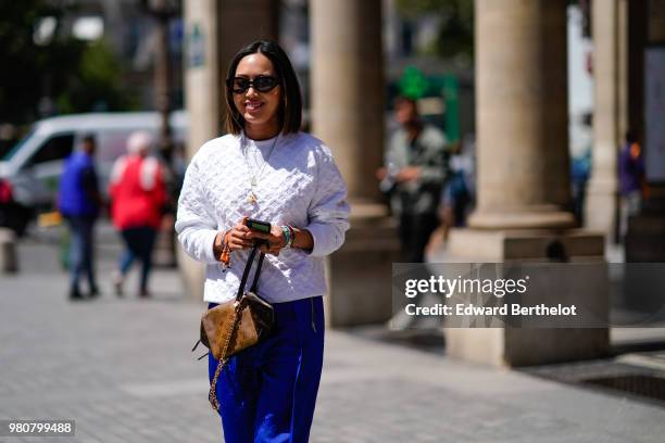 Aimee Song wears a white pullover, blue flared pants, a Vuitton bag, outside Louis Vuitton, during Paris Fashion Week - Menswear Spring-Summer 2019,...