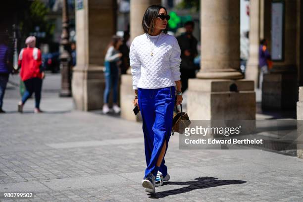 Aimee Song wears a white pullover, blue flared pants, a Vuitton bag, outside Louis Vuitton, during Paris Fashion Week - Menswear Spring-Summer 2019,...