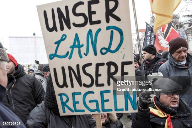 March 2018, Germany, Cottbus: A participant in the anti-refugee demonstration by the group "Zukunft Heimat" holds a sign. Photo: Carsten Koall/dpa