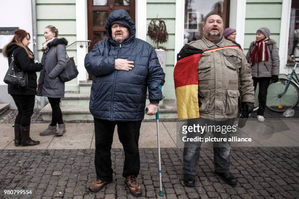 March 2018, Germany, Cottbus: Two participants in the anti-refugee demonstration by the group "Zukunft Heimat" sing the German national anthem....