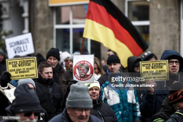 Participant holds a sign featuring German Chancellor Merkel that reads 'Das ist nicht meine Kanzlerin' during an anti-refugee demonstration orginized...