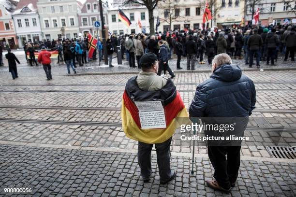 March 2018, Germany, Cottbus: Two participants in an anti-refugee demonstration by the group "Zukunft Heimat", one has draped himself in the German...
