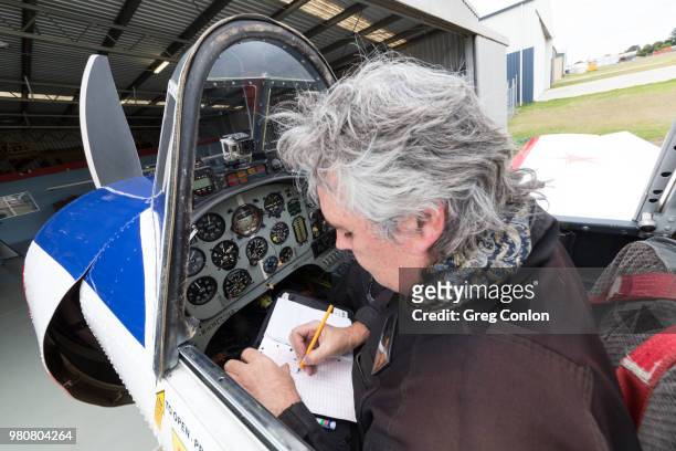 middle-aged recreational aircraft pilot filling out his logbook - toowoomba stock-fotos und bilder
