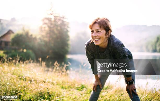 senior woman resting after exercise outdoors in nature in the foggy morning. copy space. - morning exercise stock pictures, royalty-free photos & images