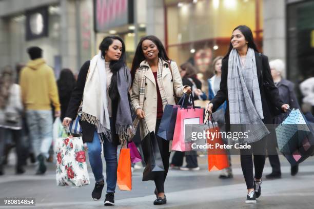 three young women in town shopping - shopping paper bag stock-fotos und bilder