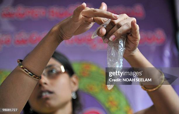 Indian programme officer G. Shilpa poses with a female condom at an awareness camp for sex workers in Hyderabad on March 27 held to acheive better...