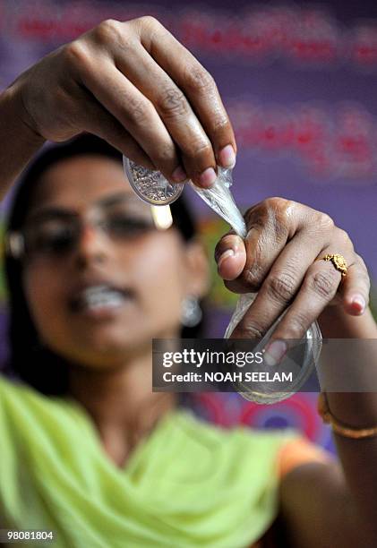 Indian programme officer G. Shilpa poses with a female condom at an awareness camp for sex workers in Hyderabad on March 27 held to acheive better...