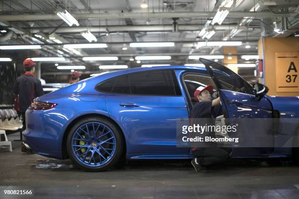 Worker polishes a Porsche AG Panamera at an auto detailing shop in the basement parking of the CentralWorld shopping mall, operated by Central...