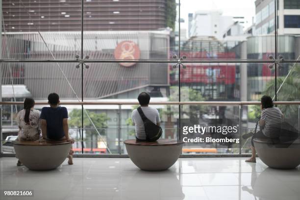 Shoppers sit looking out of windows at the CentralWorld shopping mall, operated by Central Pattana Pcl , in Bangkok, Thailand, on Saturday, June 16,...