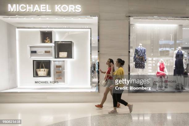 Shoppers walk past window displays for a Michael Kors Holdings Ltd. Store at the CentralWorld shopping mall, operated by Central Pattana Pcl , in...