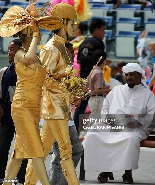 Entertainers walk past an Emirati man at the Meydan race track before the start of the Dubai World Cup, the world's richest horse race with a prize...