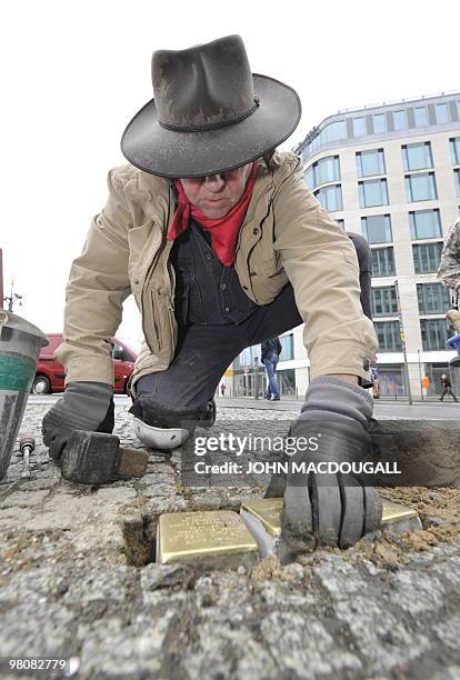 German artist Gunter Demnig lays "stolpersteine" or stumbling stones in Berlin's Friedrichstrasse March 27, 2010. The stones, topped with small brass...