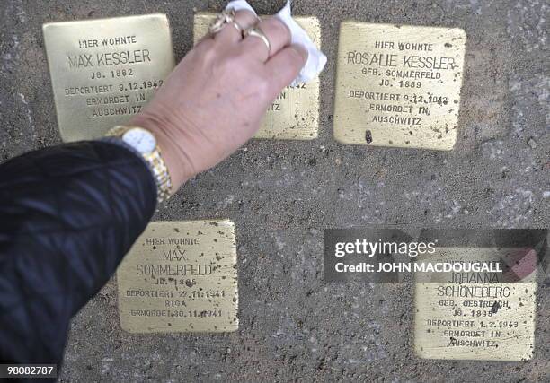 Women wipes a stolperstein after German artist Gunter Demnig layed "stolpersteine" or stumbling stones in Berlin's Friedrichstrasse March 27, 2010....